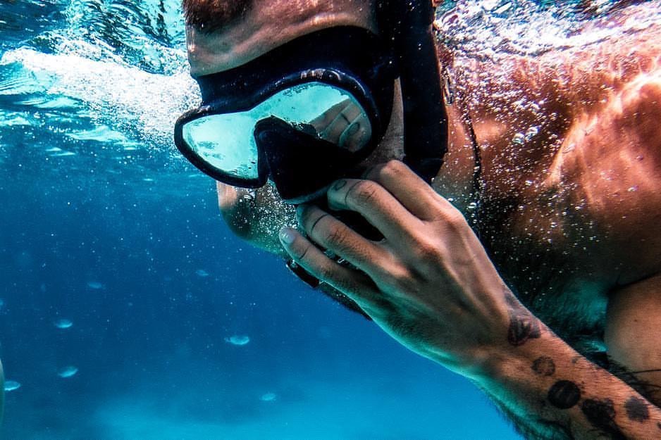 Un homme est la tête sous l'eau. Il porte un masque de plongée sous-marine Maxlux S Noir et un tuba Spy noir Beuchat. 